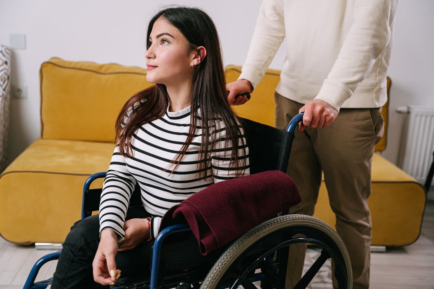 A support worker with a young woman who uses a wheelchair at home