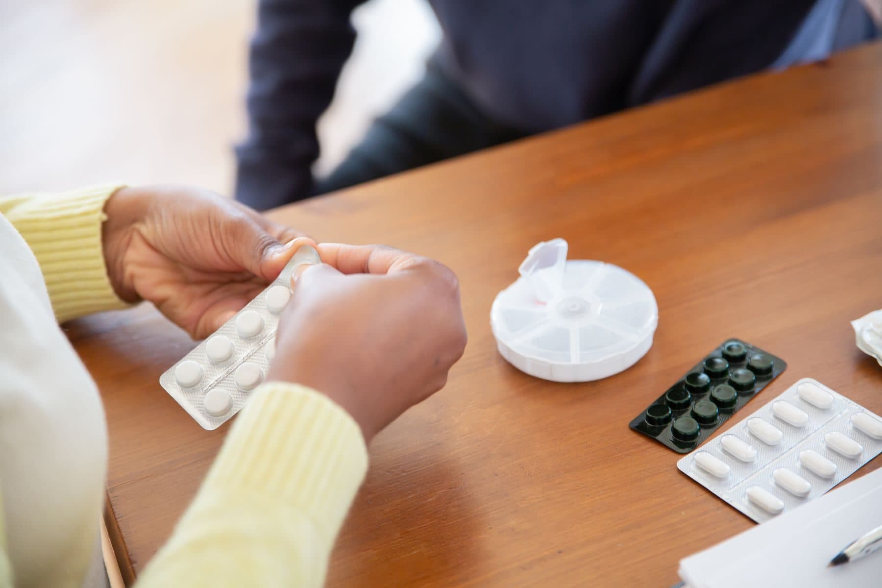 A carer helping to organise prescribed medication into a pill organiser